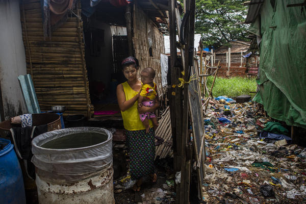 Caregiver in Myanmar holding child outside house