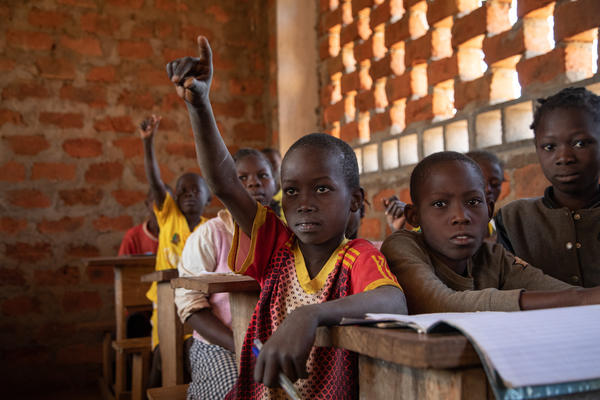 Child sitting at desk raising hand