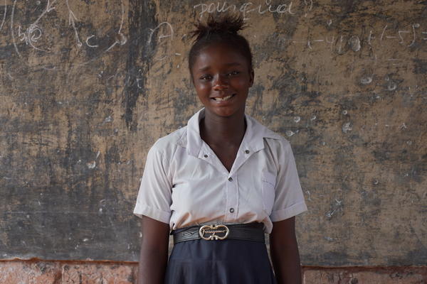 Female student in DRC standing in front of a chalk board