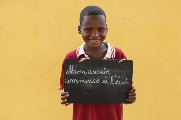 boy with blackboard that says "my future begins at school" in French