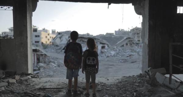 schoolchildren standing on rubble in Gaza