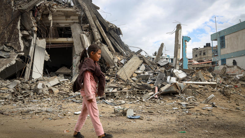 Girl walking in front of destroyed buildings in Palestine