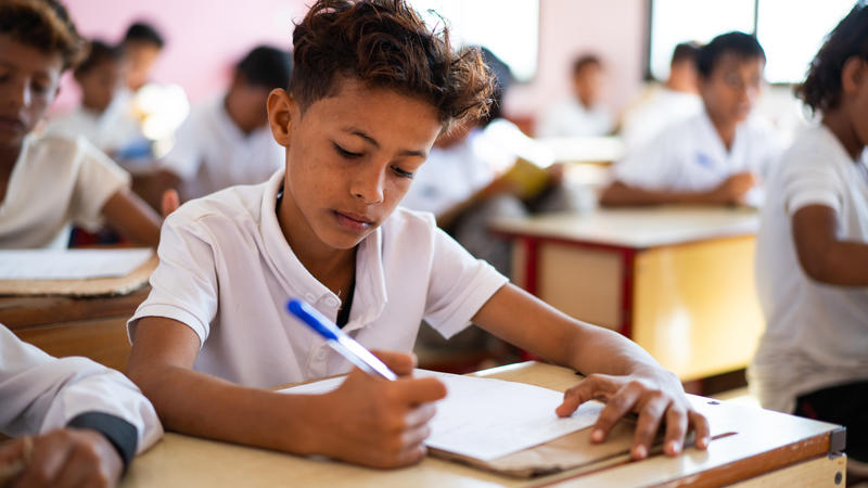 boy sitting at desk writing