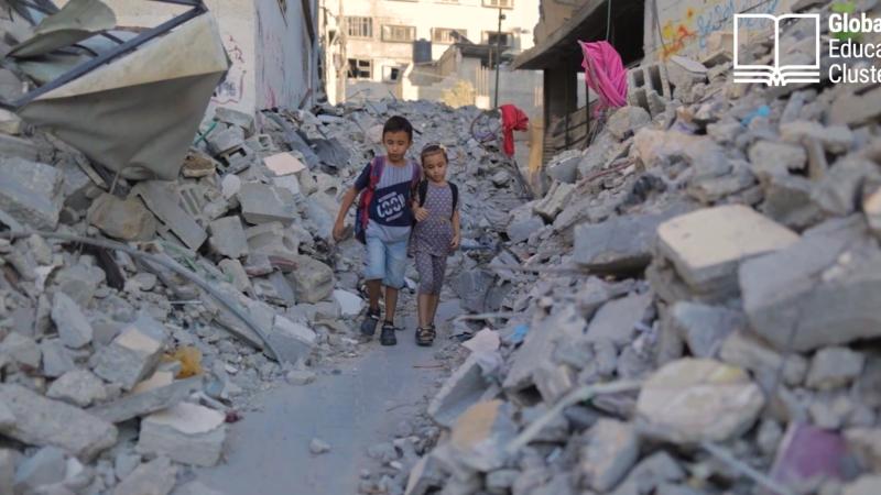 children with backpacks walking through rubble