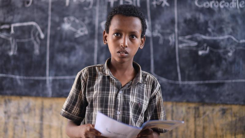 Boy in Ethiopia standing in front of chalk board